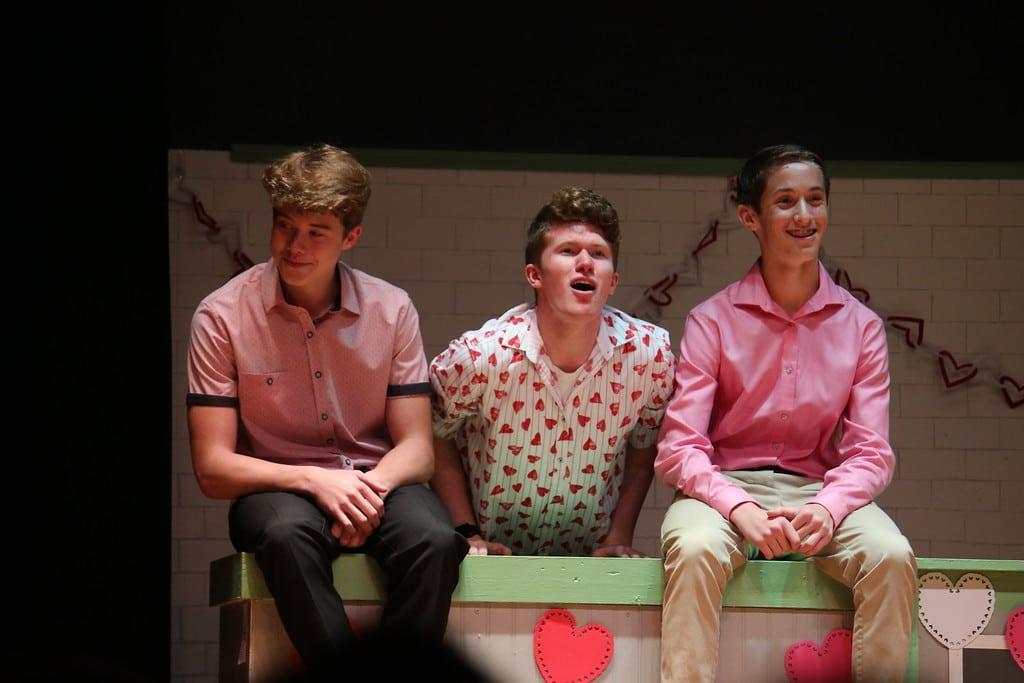 Three male students singing in theater